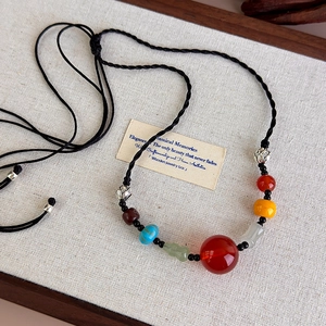 Detail of hand-woven ethnic necklace with red agate bead and colorful glass spacers