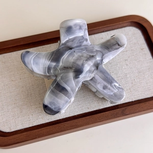 Detail of starfish hair claw featuring grey ink marble texture on elegant linen tray