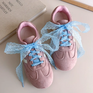 Détail de baskets en daim rose avec de larges lacets en dentelle bleue style ballet