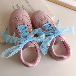 Détail de baskets en daim rose avec des lacets en dentelle bleu ciel et un style rétro