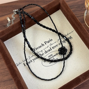 Close-up of double-layer black beaded choker with vintage rose pendant detail