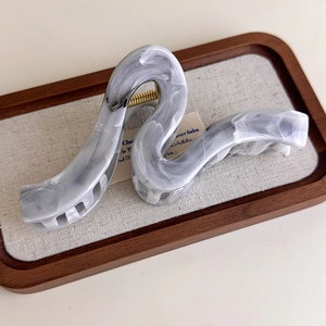 Detailed view of the wavy grey marble acetate hair claw clip with golden metal spring