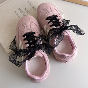 Détail de baskets en daim rose avec lacets en dentelle noire et rayures blanches