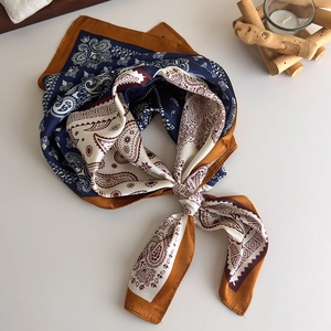 Close-up of a paisley pattern square silk scarf with knot detail on white background