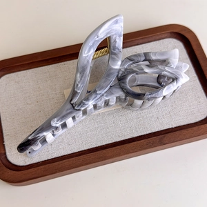 Macro detail of the gray ink pattern marble hair claw clip with golden metal spring