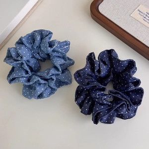 Close-up of double-layer polka dot denim scrunchies in light and dark blue cotton fabric