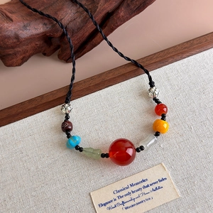 Detail of retro ethnic necklace with red agate beads and silver lotus charms on linen