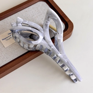 Detail of grey marble tulip claw clip with golden spring on a wooden tray