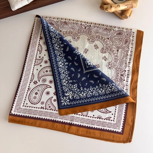 Close-up of paisley print silk scarf in navy blue and caramel with smooth satin texture