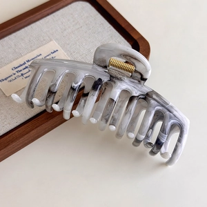 Detail of grey ink wash acetate hair claw with high quality gold metal spring