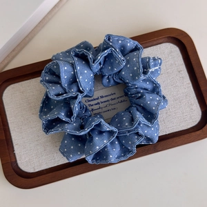 Detail of blue polka dot denim scrunchie with pleated texture on a display tray