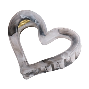 Close-up of heart hair claw with black and white marble ink texture and gold metal spring