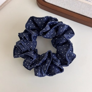 Detailed shot of dark blue polka dot denim scrunchie with layered pleated fabric texture