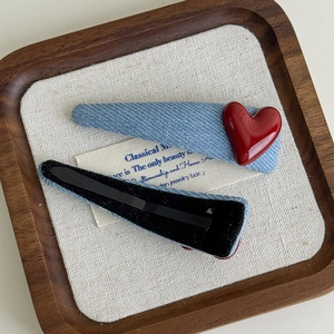 Detail of light blue denim fabric hair clips featuring a glossy red heart ornament