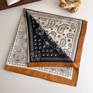 Detailed close-up of paisley pattern silk scarf with black floral print and yellow edges