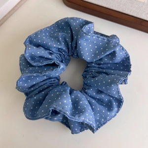 Close-up of a blue denim scrunchie with white polka dots and ruffled fabric texture