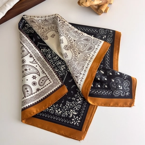 Macro detail of paisley print silk scarf with vintage gold border on white background