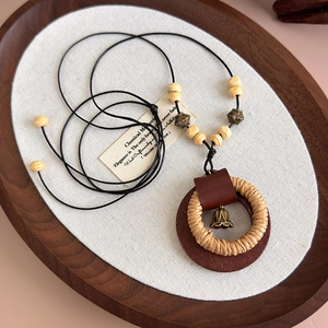 Dettaglio della collana zen in legno con corda intrecciata e ciondolo a campana