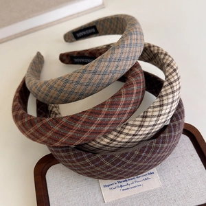 Detail of assorted plaid sponge headbands featuring classic British style on wood tray