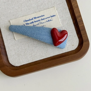 Detail view of blue denim fabric heart hair clip on a minimalist wooden tray display
