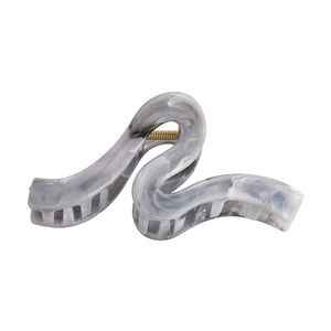 Macro detail of wave hair claw clip featuring grey marble texture and gold metal spring
