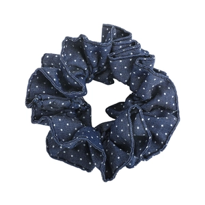 Close-up of retro navy blue polka dot denim fabric scrunchie for low ponytail styling