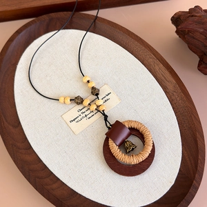Dettaglio di una collana in legno intrecciato stile Zen con anello di paglia