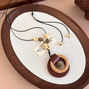 Collana etnica con doppio anello in legno e paglia su fondo in lino