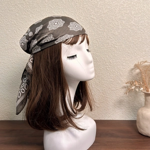 Close-up of brown geometric silk scarf with white floral patterns tied on a model head