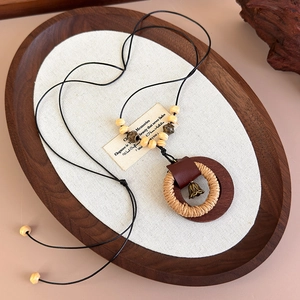 Dettaglio della collana etnica in legno con anelli intrecciati e campanello su vassoio