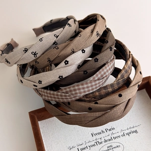 Detailed macro view of earth-toned plaid and polka dot fabric headbands in a wooden tray