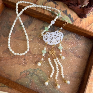 Close-up of white carved Ruyi lock pendant with pearls and tassels for Hanfu accessories