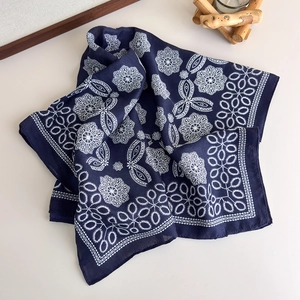 Detail of navy blue silk scarf featuring white floral patterns and delicate lace edges