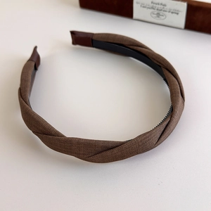 Close-up of brown braided fabric headband with anti-slip inner teeth and leather ends