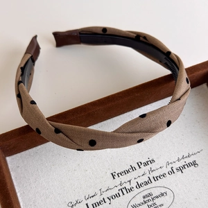 Detail of vintage polka dot twist headband with black non-slip teeth on a velvet tray