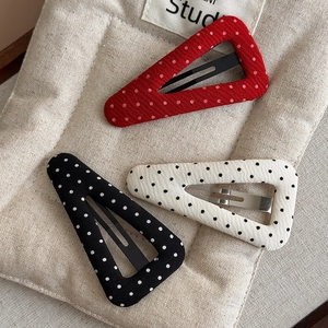 Close-up of polka dot fabric triangle hair clips in red, black, and white colors