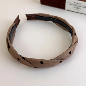 Detailed close-up of brown plaid twisted headband with anti-slip teeth and fabric texture