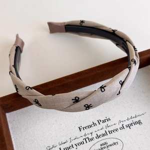 Detailed shot of beige plaid headband with black bow embroidery and non-slip inner teeth