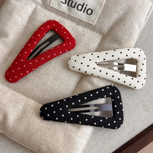 Detailed view of three polka dot fabric hair clips in red, white, and black colors