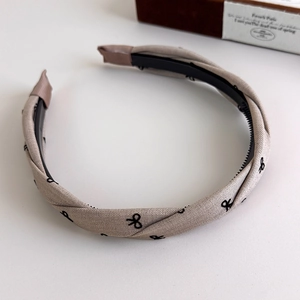 Detailed close-up of khaki plaid headband with non-slip teeth and bow print pattern