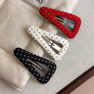 Close-up of three polka dot fabric hair clips in red, white, and black for women