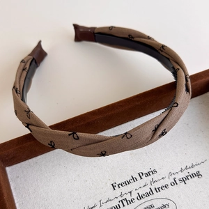 Detail view of brown twisted plaid headband with bow print and non-slip inner teeth