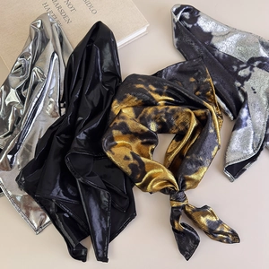 Close-up of metallic silk scarves in silver and black with leopard print texture