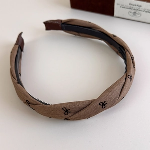 Close-up of brown plaid headband featuring fine inner teeth for secure hair styling