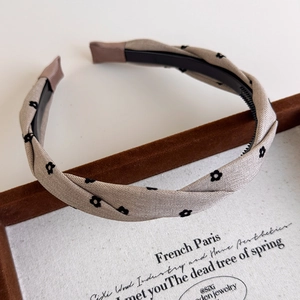 Close-up of beige plaid headband with black floral patterns and non-slip inner teeth