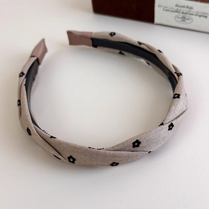 Close-up of beige fabric headband with black floral print and twisted texture detail
