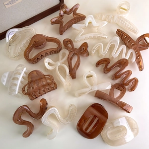 Flat lay of star and wavy geometric hair claws in cream, caramel, and clear finishes