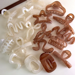 Various geometric hair claws in cream white and amber resin finishes displayed together