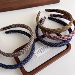 Vintage plaid padded headbands in various classic colors on a rustic wooden stand