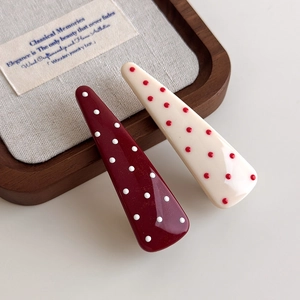 Close-up of retro red and cream polka dot acrylic hair clips on a wooden display tray